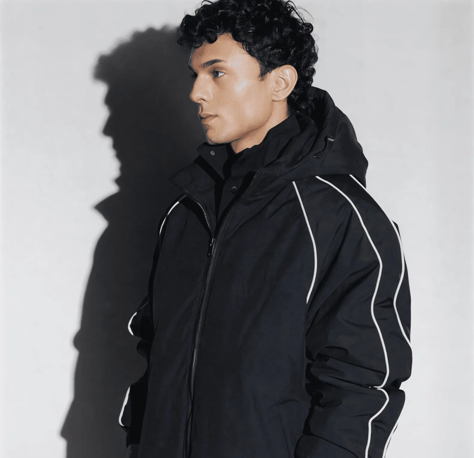 Man in a black hooded zip jacket with white piping on the sleeves