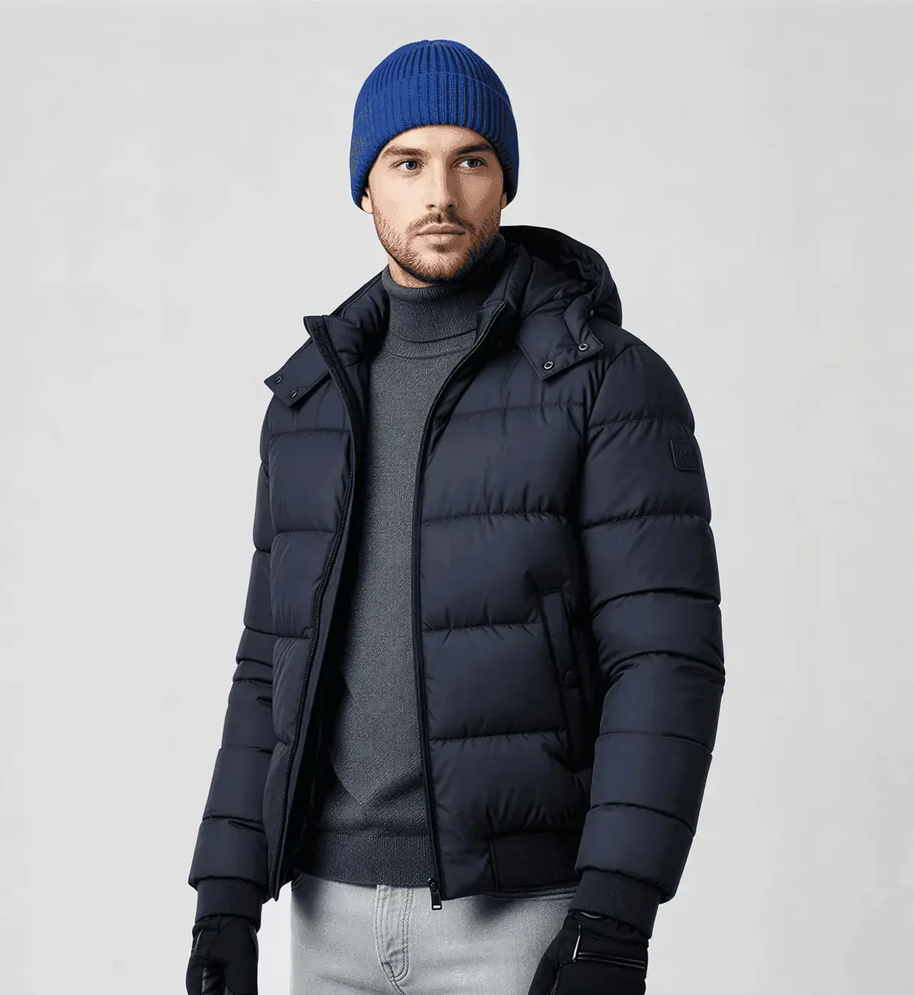 Man in a navy hooded puffer jacket, grey roll-neck and blue beanie